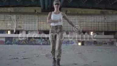 漂亮的年轻女子穿着军装，在尘土飞扬的肮脏废弃建筑的混凝土地板上朝前行进