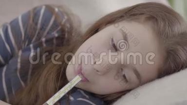 合上躺在床上的悲伤的病女，嘴里放着<strong>体温计</strong>。 生病孩子的概念.. 医学和健康。