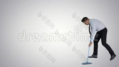 男人用拇指向上拿着扫帚，穿着正式的衣服或商业服装，在梯度背景下扫地。