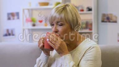 中年妇女喝着<strong>舒缓</strong>草药的热茶，恢复水的平衡