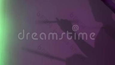 在紫色的墙壁背景上用鼓棒侧视年轻的鼓手剪影。 概念。 男影假装打鼓