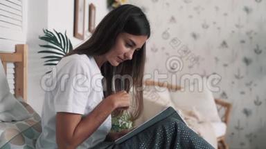 年轻的女人坐在床上，写日记，慢动作。