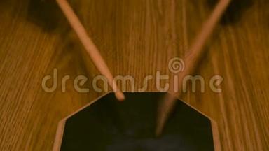 接近一个男人或女人在鼓垫上练习，鼓槌在木桌背景上。 概念。 一个人是