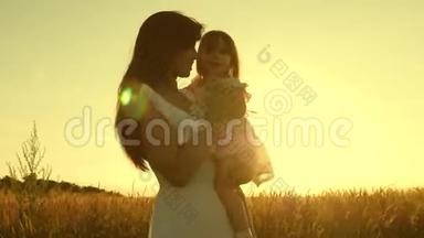 妈妈和小女儿正在阳光下的一片成熟的麦子上玩耍.. 母亲带着孩子走在麦地里