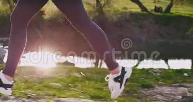 背景：日落时分，一位<strong>跑步</strong>的女士在大自然中穿过草地的特写细<strong>节</strong>，健康的生活方式