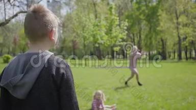 十几岁的金发男孩和他的母亲在公园玩<strong>飞盘</strong>。 小孩扔玩具，但女人抓不到
