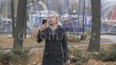 在一个荒芜的秋天公园里，一位女博主用智能<strong>手机</strong>在视频<strong>聊天</strong>上<strong>聊天</strong>。