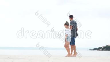 一个年轻人和两个<strong>孩子</strong>，一个男孩和一个女孩，坐在海边的白沙上。 <strong>暑假</strong>，父亲`天