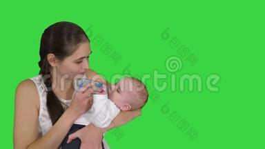 母亲抱着婴儿，用绿色屏幕上的瓶子喂婴儿，铬键。