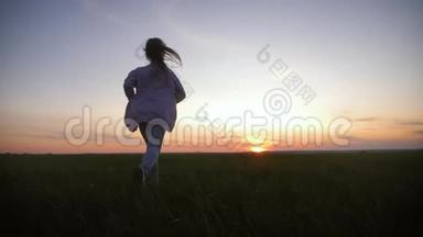 日落时分，小女孩正在草地上奔跑。 童年梦想的概念或前进的愿望。