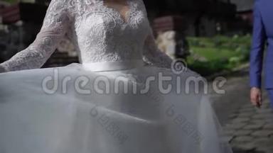 穿着婚纱的年轻新娘在公园里盘旋。 白色豪华礼服