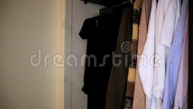 白色墙壁附近衣柜里衣服的特写镜头。概念。全衣柜内不同衬衫的侧视图