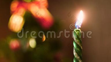 在模糊的彩色圣诞背景上点燃蜡烛。 概念。 关上绿色新年蜡烛的火焰