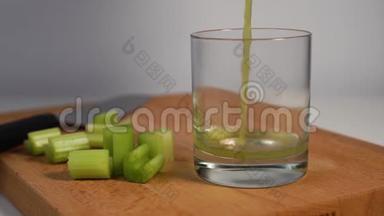 将鲜榨的芹菜汁倒入一个玻璃杯中，用刀子和切片的多汁切片放在木切割板上