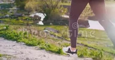 一位身材健美的女士在山路上奔跑，在令人惊叹的河景旁边奔跑双腿的细节