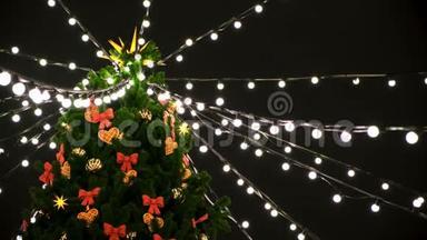 夜晚街道上装饰着玩具和花环的美丽圣诞树顶部的底部景色。 概念