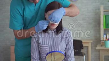男医生整形外科医生在手术后`她的脸上除去绷带