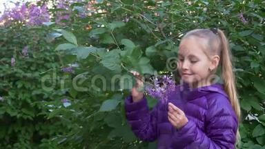 穿着紫色夹克的少女在春天的花园里嗅着丁香花。特写写真美女少年