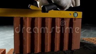 工业背景，工人手套使用锤子在水泥中铺砖。 库存录像。 接近一个使用