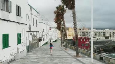 从无人驾驶飞机上看到<strong>的</strong>景象-一名妇女沿着海滨行驶，旁边是岛上首府西班牙<strong>的老房子</strong>