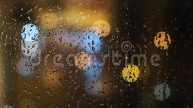 在晚上，窗外模糊的光斑和落在玻璃上的雨滴的特写。 概念