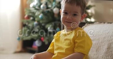 有趣的小男孩在圣诞灯的背景上微笑，可爱的<strong>宝宝看</strong>着相机，微笑着，快乐着。 快乐