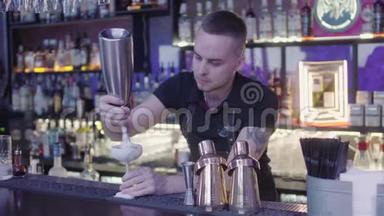 年轻的酒吧侍者站在酒吧柜台上，用一杯奶油鸡尾酒在烤架上烤着一只小猕猴桃。 长架