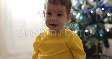 有趣的小男孩在圣诞灯的背景上微笑，可爱的宝宝看着相机，微笑着，快乐着。 快乐