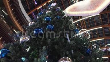 从底部看到高高的圣诞树，上面装饰着蓝银球和五颜六色的花环