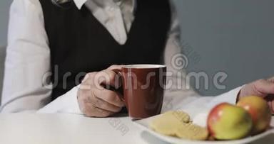 一位满脸皱纹的老妇人正在吃早餐，看着一台笔记本电脑。