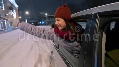年轻快乐的女人站在车窗外，在下雪的冬夜玩着火花。 漂亮女孩开车很有趣