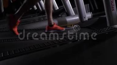 男人`脚穿红色运动鞋在跑步机上。