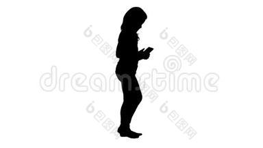 小女孩走路的时候在玩智能手机。