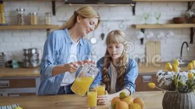 妈妈给女儿倒了一杯橙汁。 幸福的家庭在他们明亮的大家庭的餐厅里。 4千克