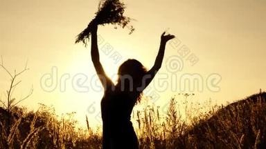 可爱的女孩挥舞着一束野花在<strong>夕阳</strong>下的<strong>夏日</strong>户外。 剪影。 快关门。 4K