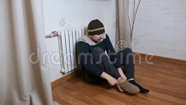 一个男人在家里戴着帽子和<strong>温暖</strong>的衣服，沐浴在<strong>温暖</strong>的电池里。 寒冷的冬霜