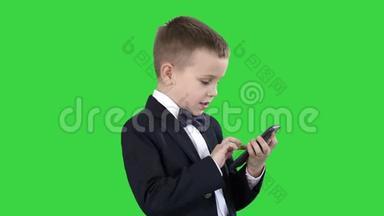 年轻男孩穿着优雅的西装，在绿色屏幕上<strong>玩手机</strong>，Chroma键。