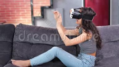 在沙发上戴着虚拟现实模拟眼镜玩游戏的赤脚微笑年轻女子