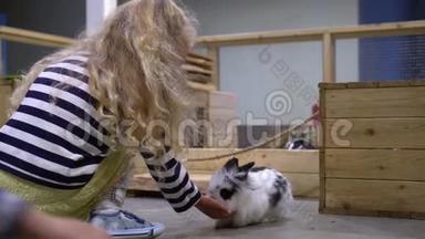 金发小<strong>女孩</strong>在动物园喂<strong>兔子</strong>。 幼儿男孩像<strong>兔子</strong>一样跳