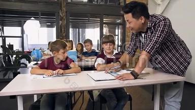年轻的韩国男教师帮助小学生在课堂上学习功课