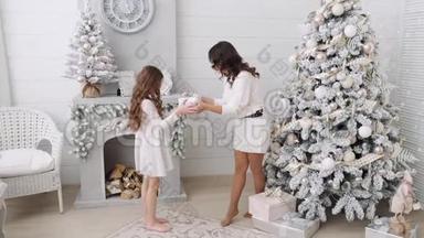 妈妈和女儿在美丽的圣诞节室内背景下互相赠<strong>送礼</strong>物。 家庭母亲和