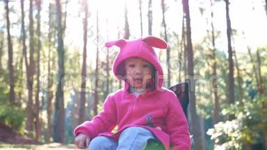 亚洲小女孩坐在椅子上，和家人一起去松林露营。 户外活动的概念
