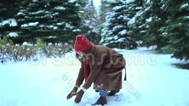 穿着针织围巾和帽子的年轻漂亮女人在公园里玩雪球。 冬季时尚