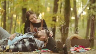 秋天的一对。 一对夫妇坐在公园里秋天的落叶上。 微笑的夫妇在秋天公园玩得很开心。 好好享受
