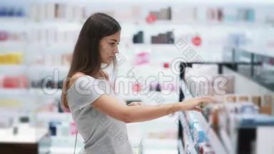 漂亮的女孩在<strong>化妆品店</strong>里选择香水，喷在测试仪上，慢动作