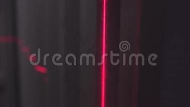 男人的剪影在黑暗中用条形码扫描仪的红线把厚厚的线夹在墙上。 库存录像。 关闭
