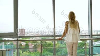 从窗外眺望城市风景的金发美女的后景