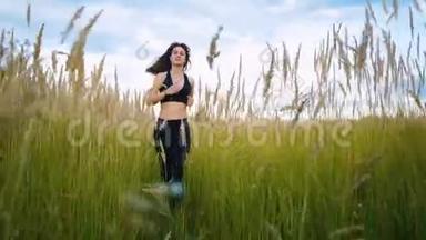 适合女人慢跑锻炼跑步的心脏户外通过高大的草地在夏季的田野。 女跑步运动员。