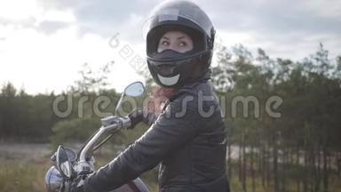 自信的女孩戴着黑色头盔坐在摩托车上<strong>回头</strong>看路。 爱好，旅游和活动