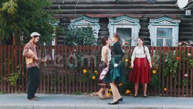 穿着长裙的年轻女子在村里的街道上用音乐跳舞